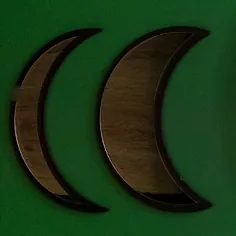 Two wooden crescent moons on a deep green wall.